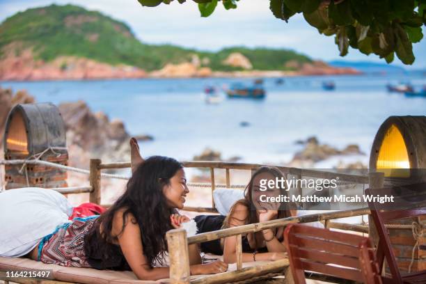 girlfriends hang out together on a scenic beachfront chair. - vietnam strand stock pictures, royalty-free photos & images
