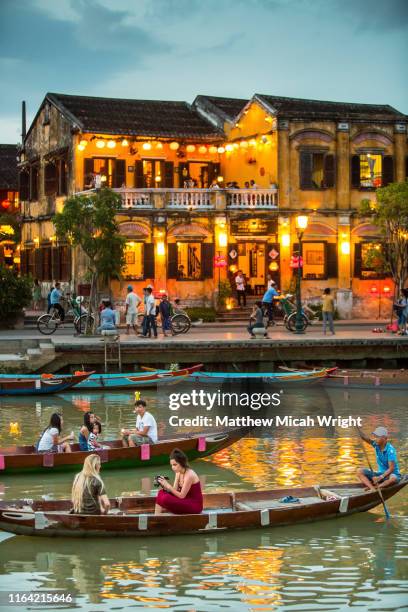 boating along the river at sunset on the hoi an river. colonial buildings line the shoreline. - hoi an stockfoto's en -beelden