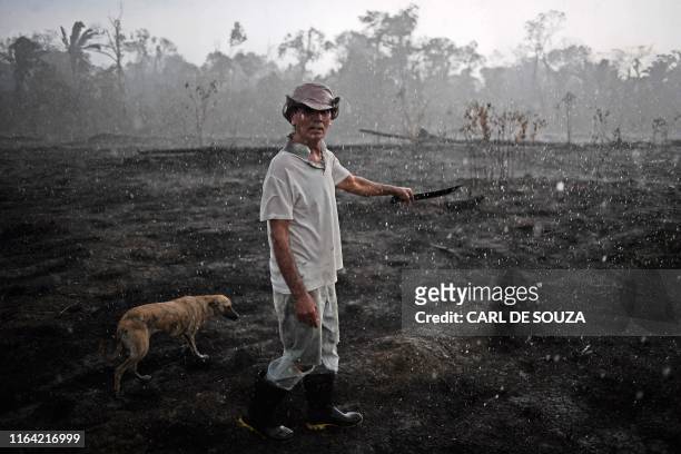 Brazilian farmer Helio Lombardo Do Santos and a dog walk through a burnt area of the Amazon rainforest, near Porto Velho, Rondonia state, Brazil, on...