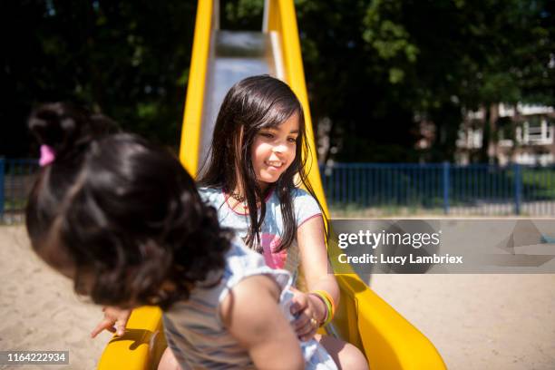 girls at playground: two sisters at the bottom of a slide - kid sliding stock pictures, royalty-free photos & images