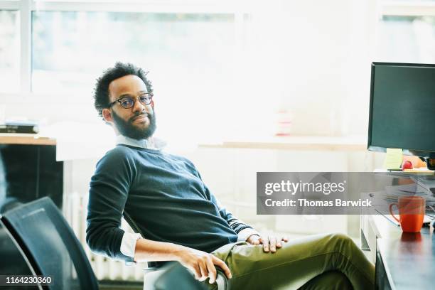 portrait of businessman seated at workstation in office - confident desk man text space stock pictures, royalty-free photos & images