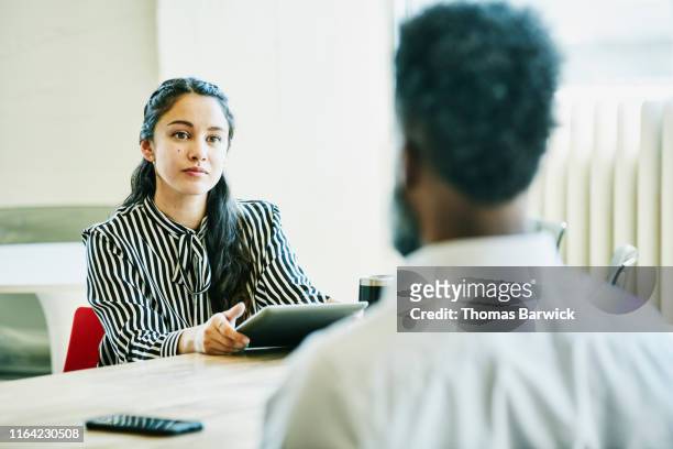 Businesswoman holding digital tablet working with client in office conference room