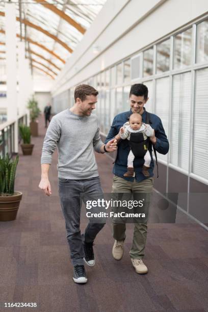 due papà portano la loro bambina al centro commerciale - surrogato foto e immagini stock