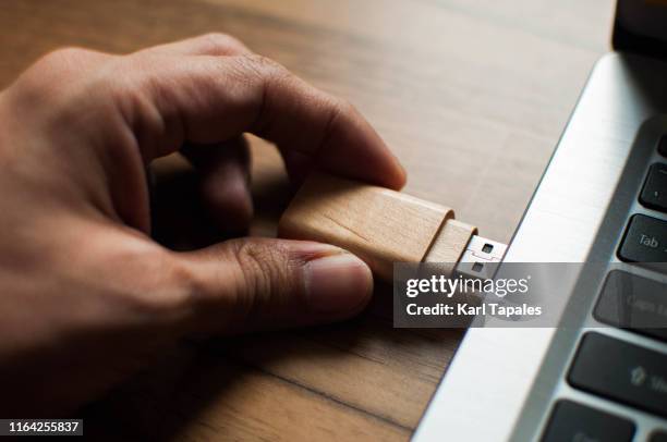 a young person is inserting a usb stick in a laptop computer - usb stick stock-fotos und bilder