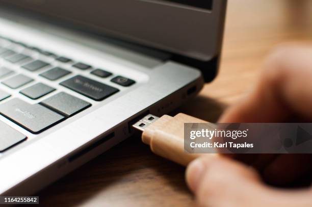 a young person is inserting a usb stick in a laptop computer - pen drive - fotografias e filmes do acervo