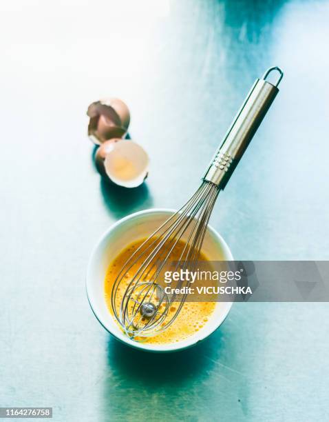 beaten egg in a bowl with a whisk - whisk foto e immagini stock
