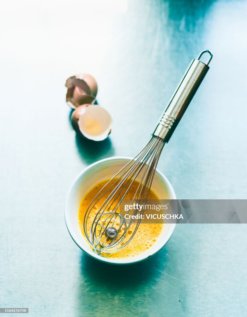 Beaten egg in a bowl with a whisk