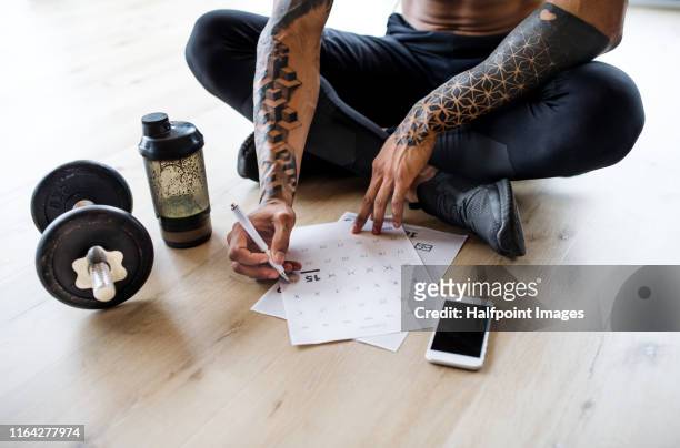 a midsection of fit mixed race man with smartphone doing exercise at home, checking progress. - checking sports fotografías e imágenes de stock