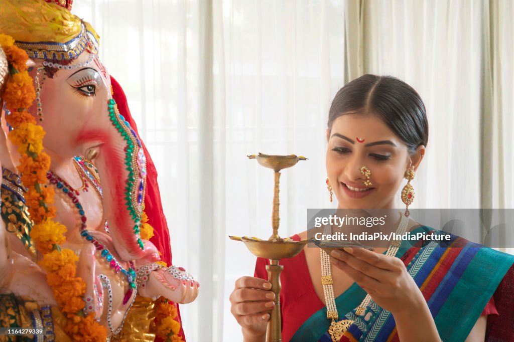 Woman lighting up the diya preparing for Ganpati pooja on Ganesh Chaturthi
