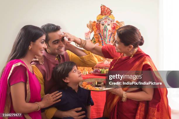 family celerating ganesh chaturthi where grandmother applies tilak to everybody. - arctis stock pictures, royalty-free photos & images