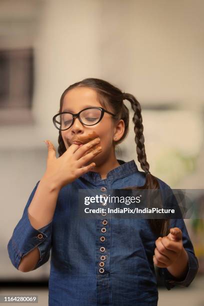 girl in spectacles licking her fingers after eating chocolate - girls licking girls stock pictures, royalty-free photos & images