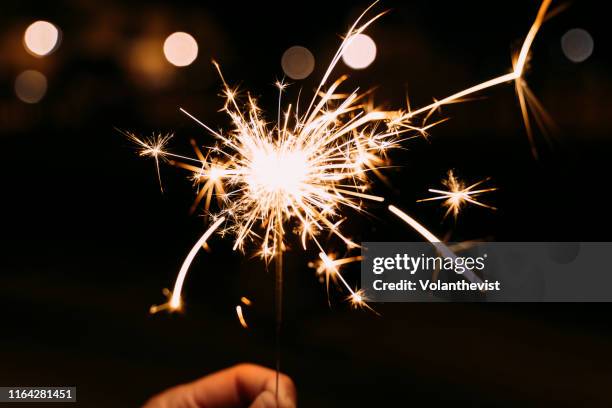 hand holding a burning sparkler at a party - bengala fuego artificial fotografías e imágenes de stock