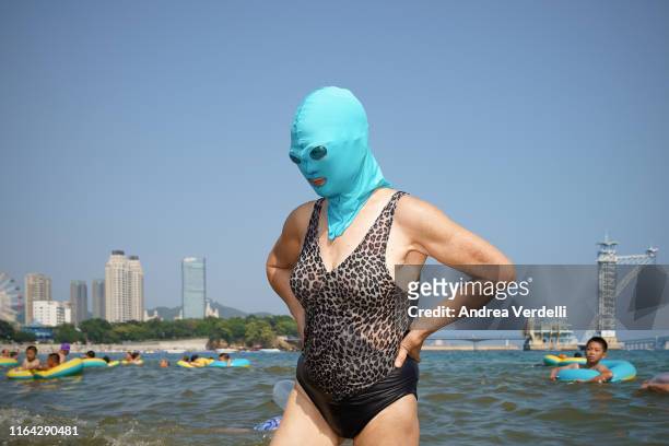 Woman wears a facekini and stands on the beach. On July 18, 2019 in Dalian, China. As temperatures have recently surged in most parts of China, many...