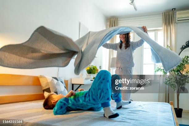 mother playing with her son, throwing bed sheet in the air - flip over stock pictures, royalty-free photos & images