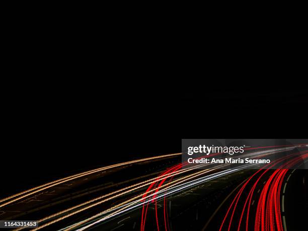 lights and trails of vehicles, cars and trucks, driving along a road with a curve at nightfall. - vehicle light stockfoto's en -beelden