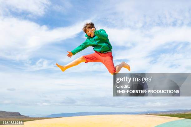 cute and young boy is bouncing off an air trampoline - ems sport stock-fotos und bilder