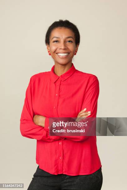 ritratto in studio di un'attraente donna di 30 anni con una camicia rossa su sfondo beige - top capo di vestiario foto e immagini stock