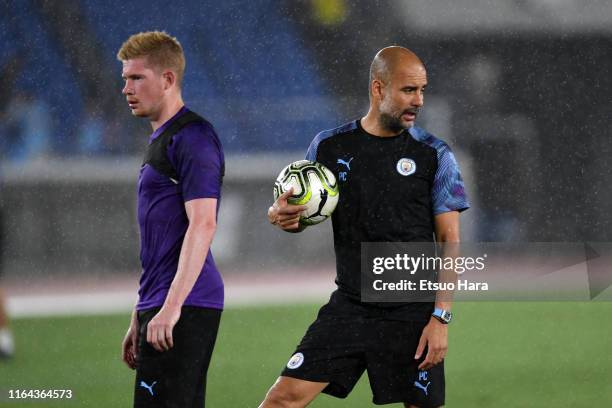 Manchester City manager Pep Guardiola and Kevin De Bruyne look on during a Manchester City training session at the Nissan Stadium on July 26, 2019 in...