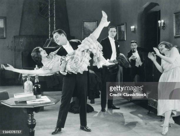 1920s Movie Still Of Wild Party With Woman Flapper Turned Upside-Down In Arms Of Man Dancing