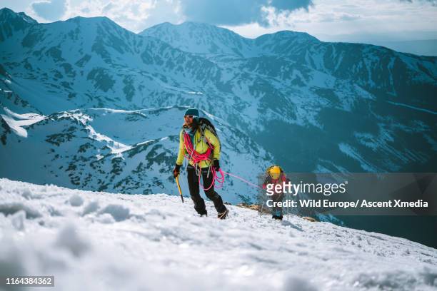 Mother and daughter climb up a mountain in winter