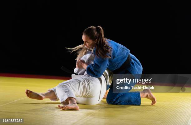 two female judo practitioners grappling on a tatami mat - female wrestling stock pictures, royalty-free photos & images