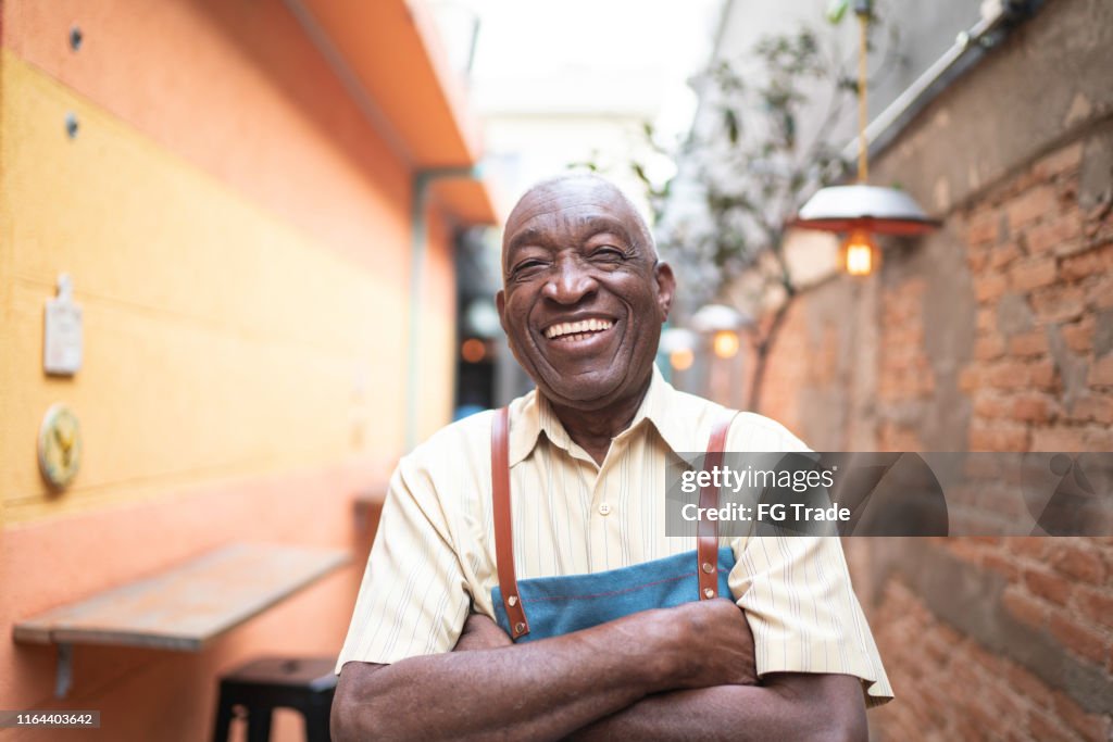 Porträt eines lächelnden alten Kellners, der in die Kamera schaut