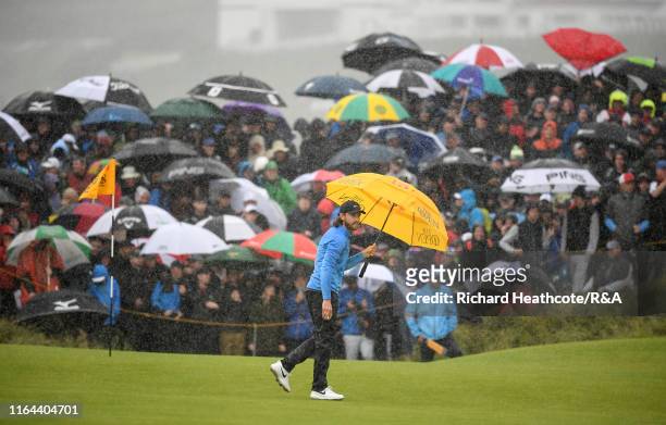 Tommy Fleetwood of England shelters under his umbrella in heavy rain on the 8th green during the final round of the 148th Open Championship held on...
