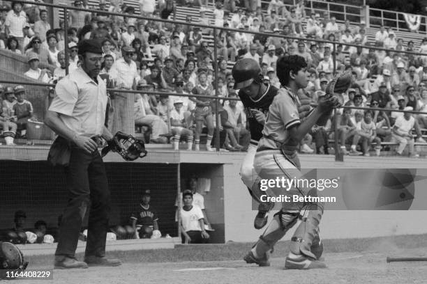 Wu Chun-Liang of the Taiwan Little League team, crosses home plate behind Venezuela's catcher Yohel Pozo to score the go-ahead run in their...