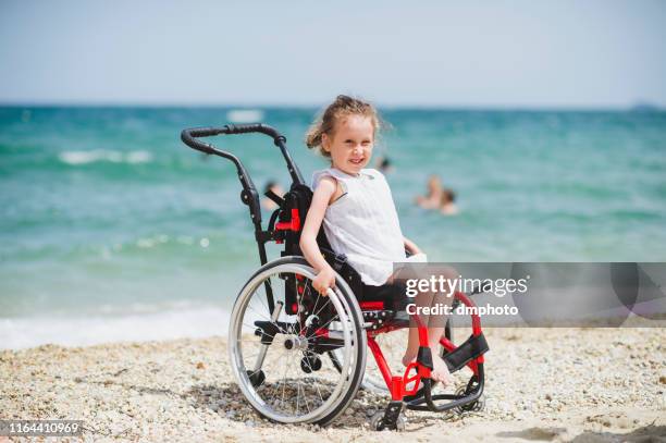 cute little girl on the wheelchair by the sea - atrophy stock pictures, royalty-free photos & images