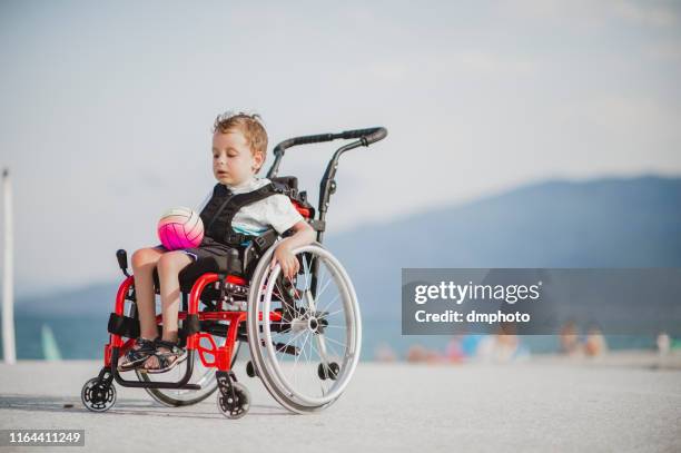 cute young boy on the wheelchair by the sea - atrophy stock pictures, royalty-free photos & images