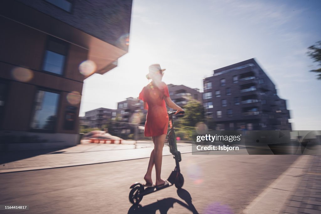 Achteraanzicht van de vrouw op elektrische scooter.
