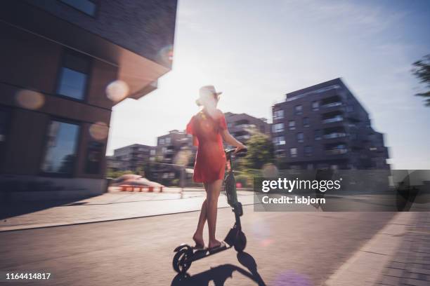 rear view of female on electric scooter. - motor cart stock pictures, royalty-free photos & images