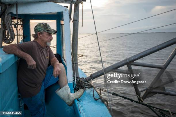 Longtime shrimper Acy Cooper, keeps an eye on his nets as he begins a 12 hour plus overnight shift of shrimping on August 26, 2019 off the coast of...