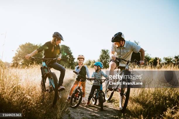 family mountain bike riding together on sunny day - ciclismo fotografías e imágenes de stock