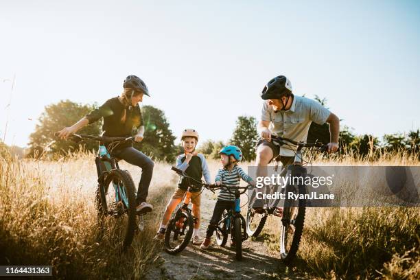 family mountain bike riding together on sunny day - bicycle trail outdoor sports stock pictures, royalty-free photos & images