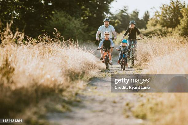 family mountain bike riding together on sunny day - cycling helmet stock pictures, royalty-free photos & images