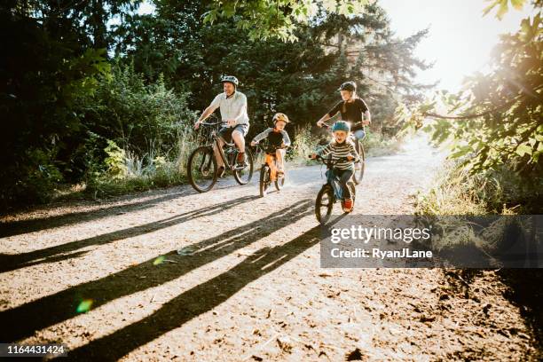 vélo de montagne de famille équitation ensemble le jour ensoleillé - chemin de terre photos et images de collection