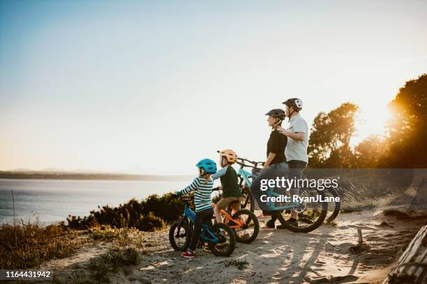 family mountain bike riding together on sunny day - puget sound stock pictures, royalty-free photos & images