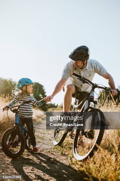 father and daughter mountain bike riding together on sunny day - family biking stock pictures, royalty-free photos & images