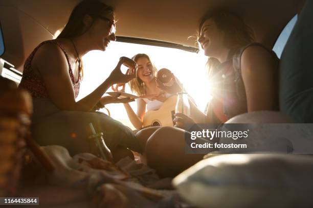 girlfriends enjoying snacks while camping in a car - friends inside car imagens e fotografias de stock