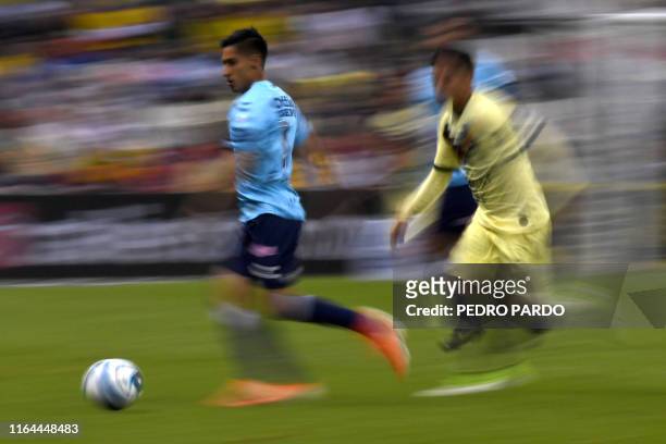 Photograph taken with a slow shutter speed shows Pachuca's midfielder Erick Aguirre battling for the ball with America's midfielder Leonel Lopez...