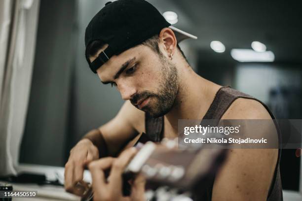 a man with a cap and a guitar - man sitting on bean bag stock pictures, royalty-free photos & images