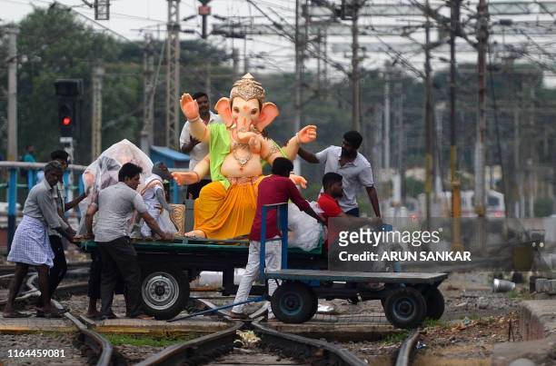 Workers transport an idol of Hindu Lord Ganesh across railroad tracks ahead of the upcoming "Ganesh Chaturthi" Hindu festival, in Chennai on August...