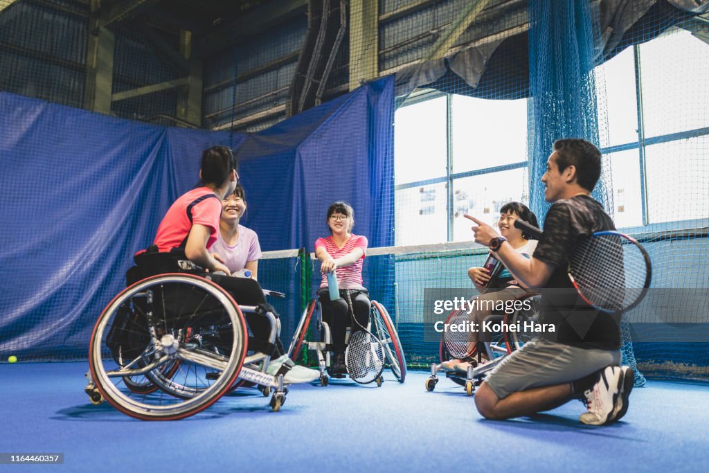Wheel chair tennis team having a meeting with their coach in the tennis court