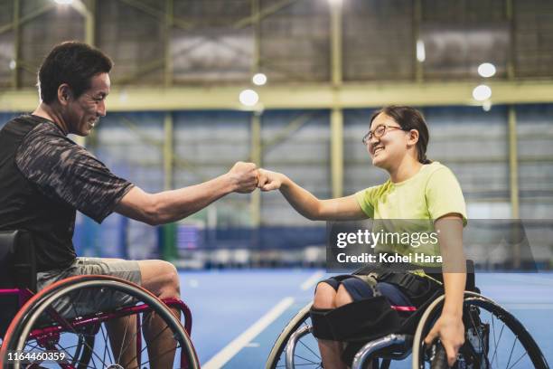 disabled female athlete doing a fist bump with her coach during playing wheel chair tennis - japanese tennis photos et images de collection