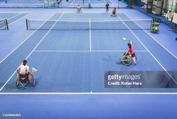 Disabled female athletes playing wheel chair tennis with their coach