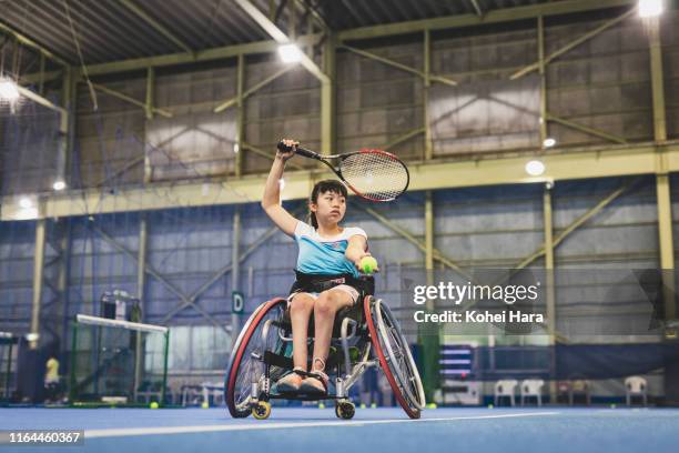 disabled female athletes serving during playing wheel chair tennis - drive ball sports stock-fotos und bilder