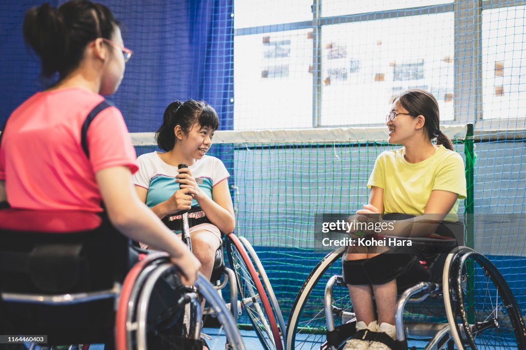 Disabled female athletes talking while playing wheel chair tennis