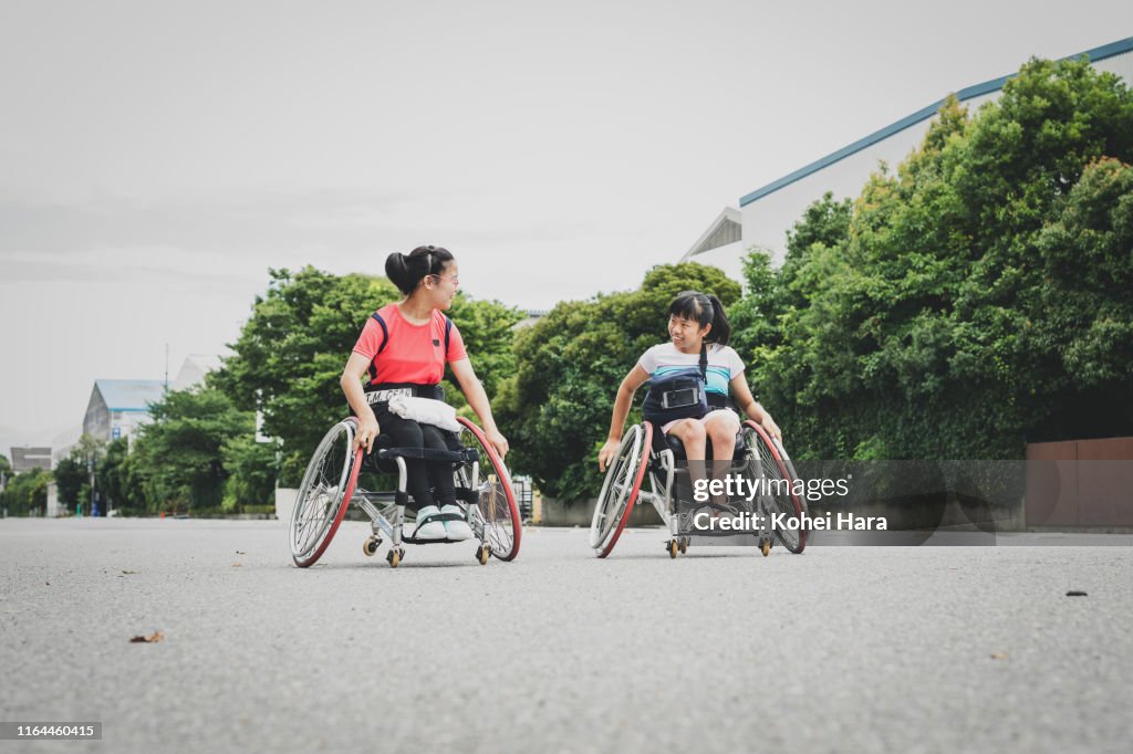 Disabled female athletes on wheel chair for wheel chair tennis walking together on the road
