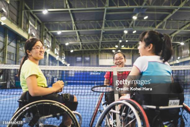 Disabled female athletes talking while playing wheel chair tennis